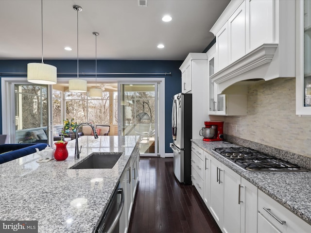 kitchen with dark wood finished floors, a sink, glass insert cabinets, appliances with stainless steel finishes, and tasteful backsplash