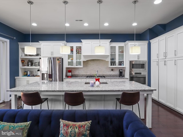 kitchen with a breakfast bar area, dark wood-style floors, visible vents, and appliances with stainless steel finishes