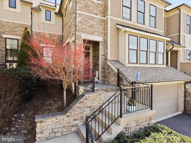 property entrance featuring stone siding, an attached garage, and driveway