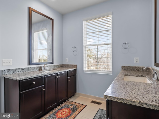 bathroom with two vanities, visible vents, baseboards, and a sink