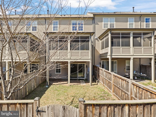 rear view of house featuring a lawn, a fenced backyard, and a sunroom