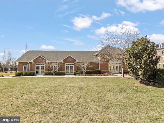 view of front facade featuring brick siding, french doors, and a front yard