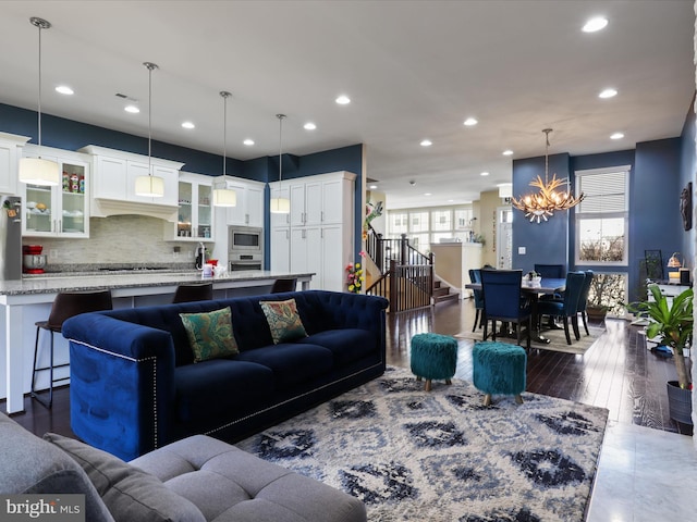 living room with recessed lighting, a notable chandelier, dark wood-style floors, and stairs