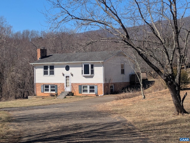 raised ranch featuring brick siding and a chimney