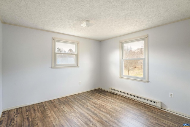 spare room with baseboard heating, a healthy amount of sunlight, a textured ceiling, and wood finished floors