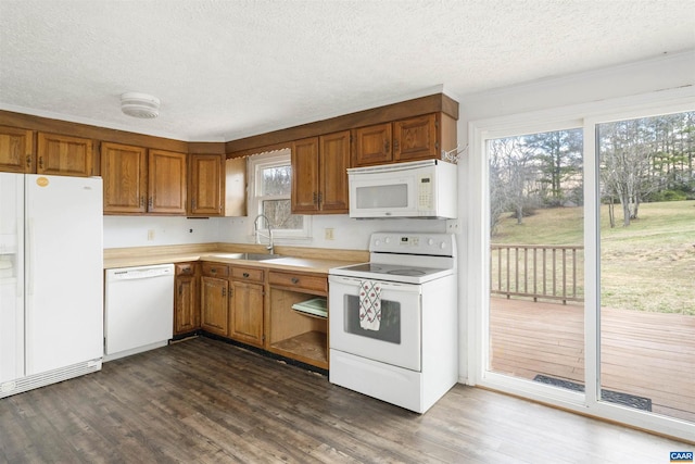 kitchen featuring dark wood-style flooring, white appliances, light countertops, and a sink