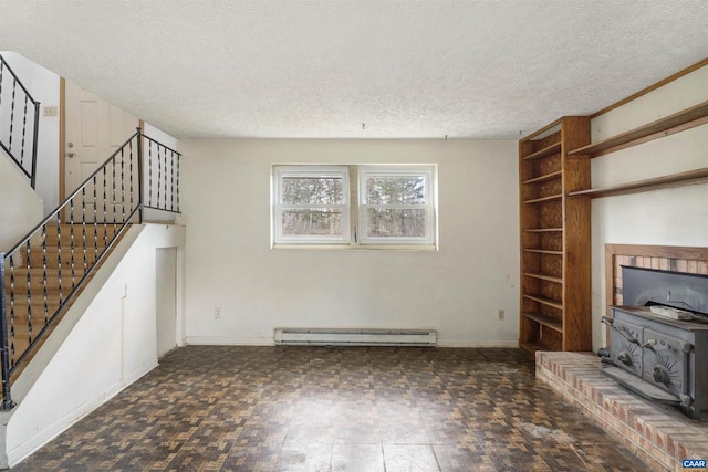 unfurnished living room with a baseboard heating unit, a textured ceiling, stairway, baseboards, and a wood stove