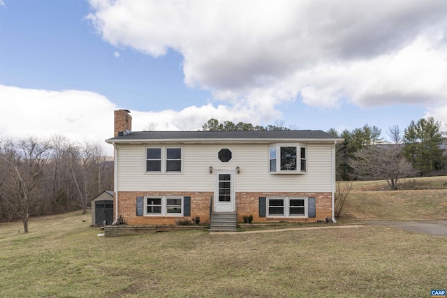 raised ranch featuring brick siding, a chimney, a front yard, and entry steps