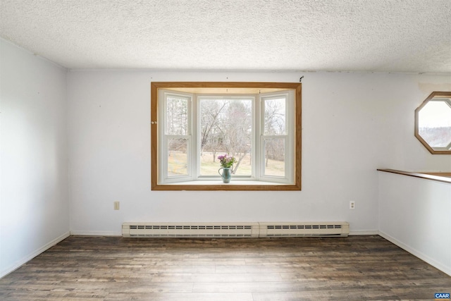 empty room with a textured ceiling, a baseboard heating unit, baseboards, and wood finished floors