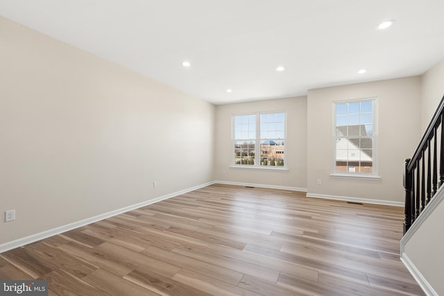 unfurnished living room with recessed lighting, light wood-style flooring, stairs, and baseboards