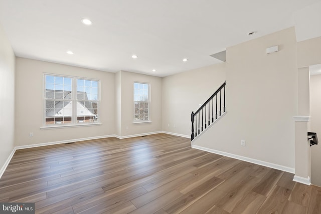 unfurnished living room featuring recessed lighting, stairway, baseboards, and wood finished floors