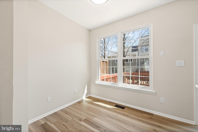 unfurnished room featuring visible vents, baseboards, and wood finished floors