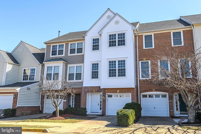 multi unit property with brick siding, driveway, and a garage