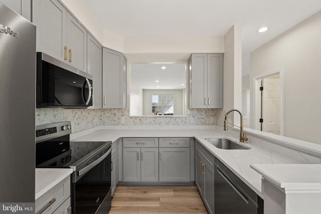 kitchen featuring a sink, light wood-type flooring, gray cabinets, and stainless steel appliances