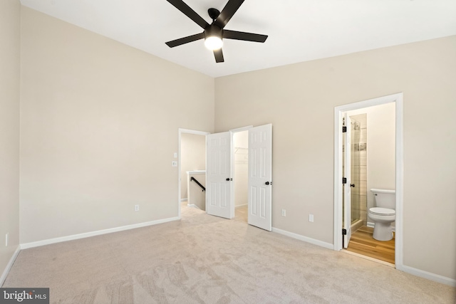 unfurnished bedroom with a walk in closet, baseboards, carpet floors, and connected bathroom