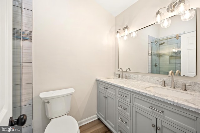 bathroom featuring a shower stall, toilet, double vanity, and a sink