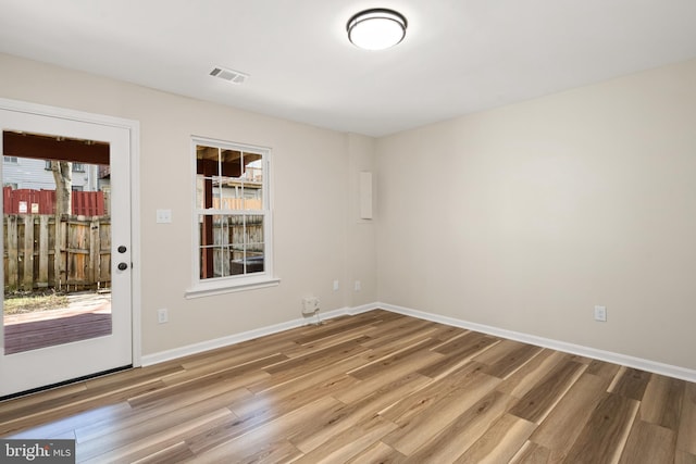 spare room with visible vents, baseboards, and wood finished floors