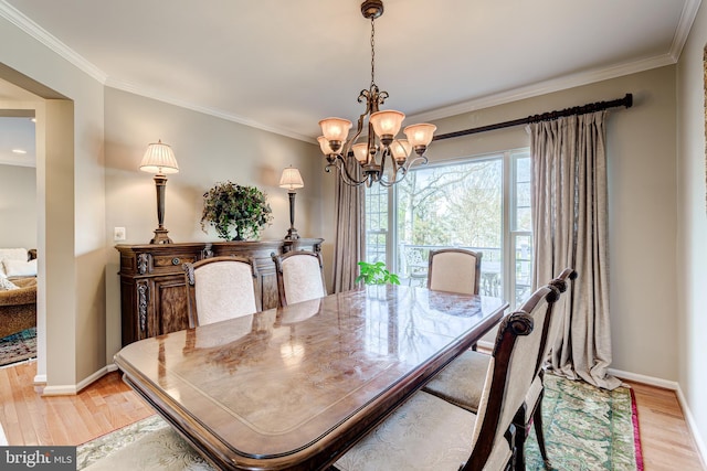 dining room featuring light wood-style flooring, baseboards, an inviting chandelier, and ornamental molding