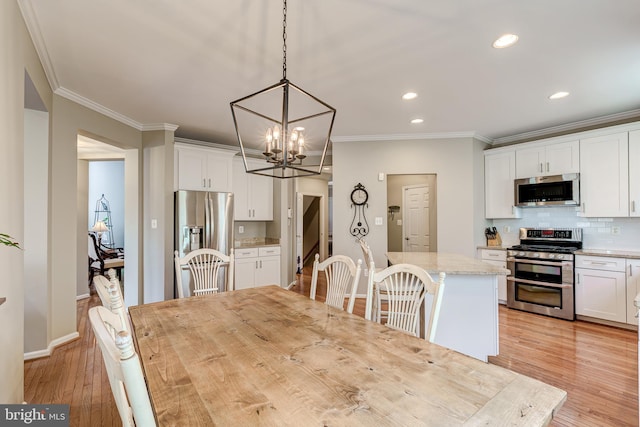 dining space with a notable chandelier, baseboards, light wood-style floors, and crown molding