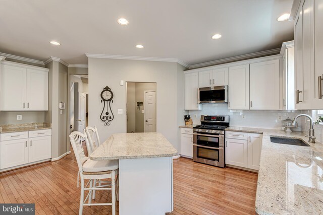 kitchen featuring light wood-style flooring, white cabinets, stainless steel appliances, and a sink