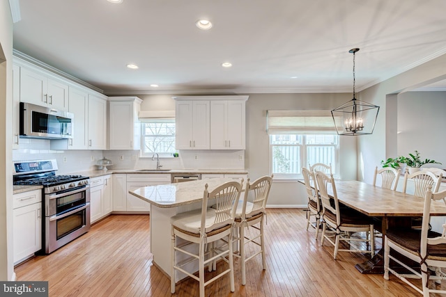 kitchen with tasteful backsplash, crown molding, appliances with stainless steel finishes, white cabinetry, and a sink