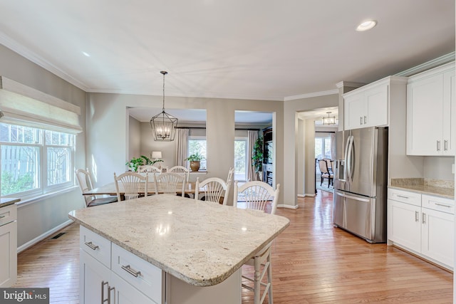 kitchen featuring a kitchen breakfast bar, light wood-style floors, ornamental molding, and stainless steel refrigerator with ice dispenser