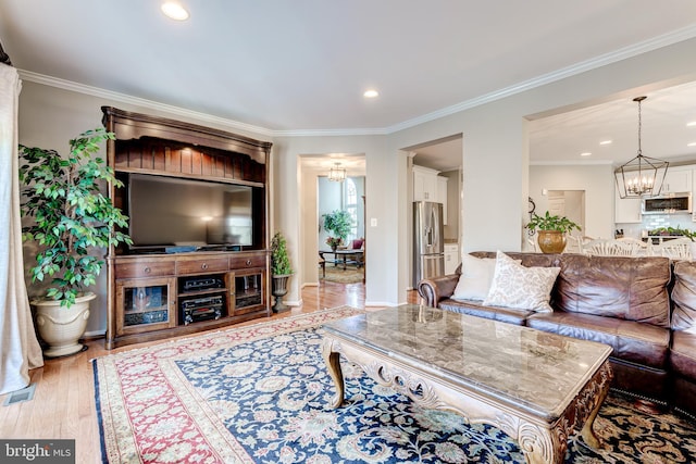 living room with an inviting chandelier, crown molding, recessed lighting, and wood finished floors