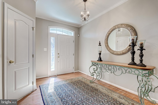 foyer featuring baseboards, wood finished floors, an inviting chandelier, and ornamental molding