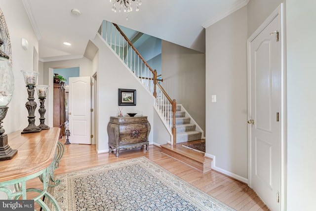 foyer featuring stairs, wood finished floors, baseboards, and ornamental molding