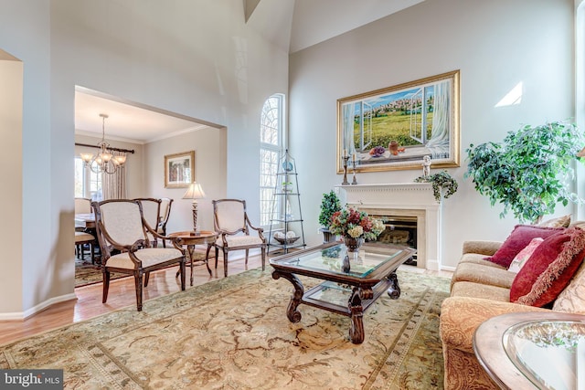 living room featuring wood finished floors, baseboards, a high ceiling, a fireplace, and a chandelier