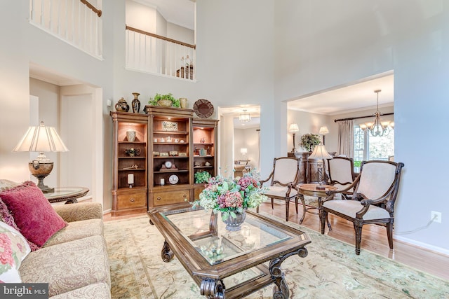 living area featuring a chandelier, baseboards, wood finished floors, and a towering ceiling