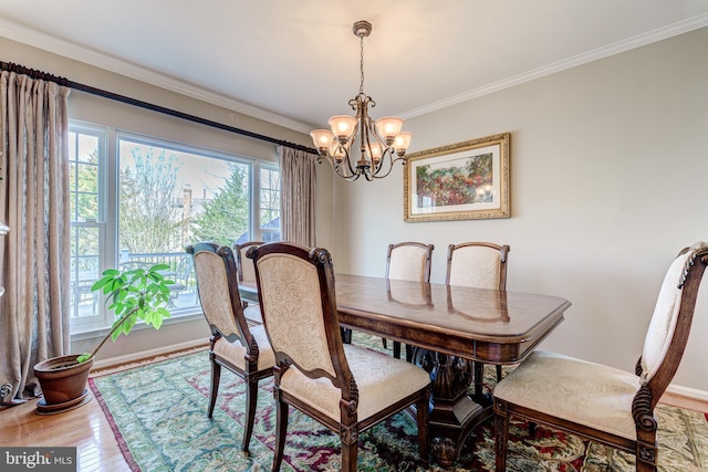 dining room featuring baseboards, wood finished floors, an inviting chandelier, and ornamental molding