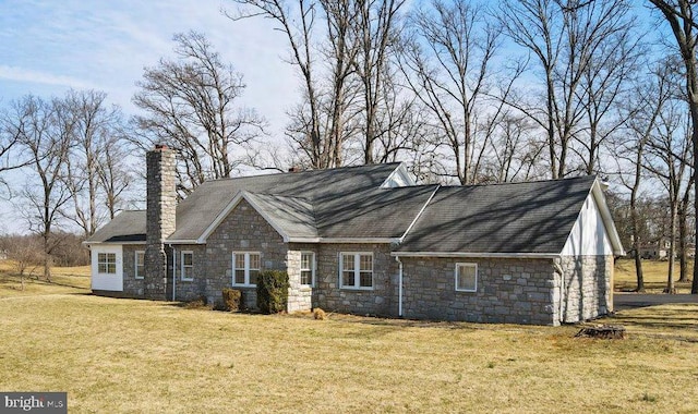 view of side of property with a lawn, stone siding, and a chimney