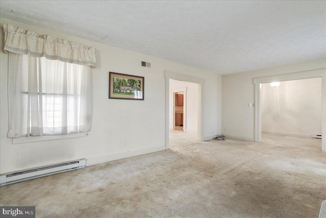 carpeted empty room featuring a baseboard heating unit, baseboards, and visible vents