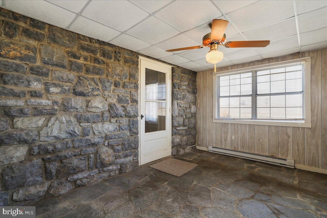 unfurnished room featuring a baseboard heating unit, a drop ceiling, and ceiling fan