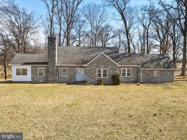 back of house featuring a yard, stone siding, roof with shingles, and a chimney