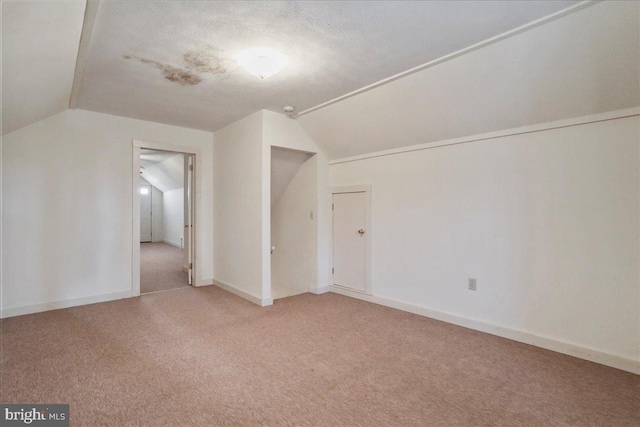 additional living space with vaulted ceiling, baseboards, and light carpet