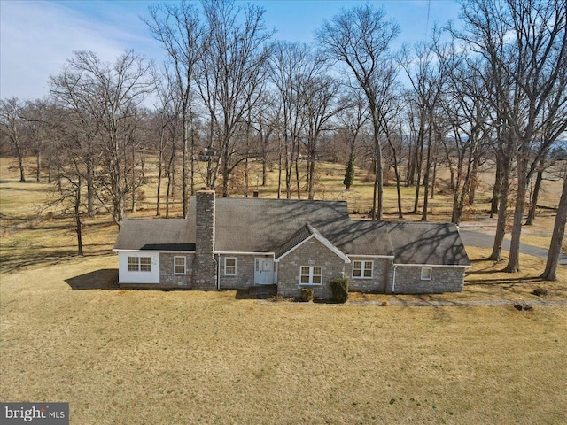 view of front of house featuring a front yard, stone siding, and a chimney