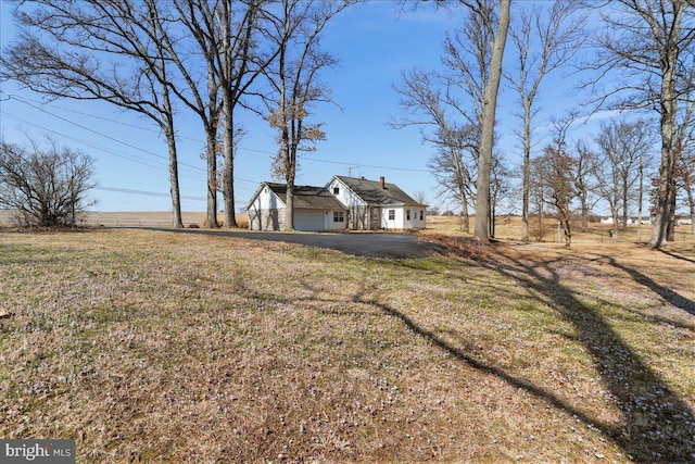 view of yard featuring aphalt driveway and a garage