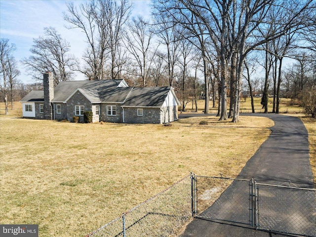 view of front of home with a gate, fence, a chimney, a front lawn, and aphalt driveway