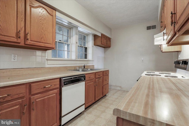 kitchen featuring white appliances, brown cabinetry, light floors, visible vents, and a sink