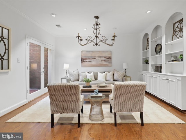 living room featuring wood finished floors, an inviting chandelier, recessed lighting, french doors, and crown molding