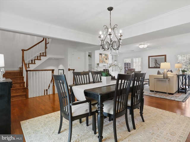 dining area with stairway, wood finished floors, a chandelier, and ornamental molding