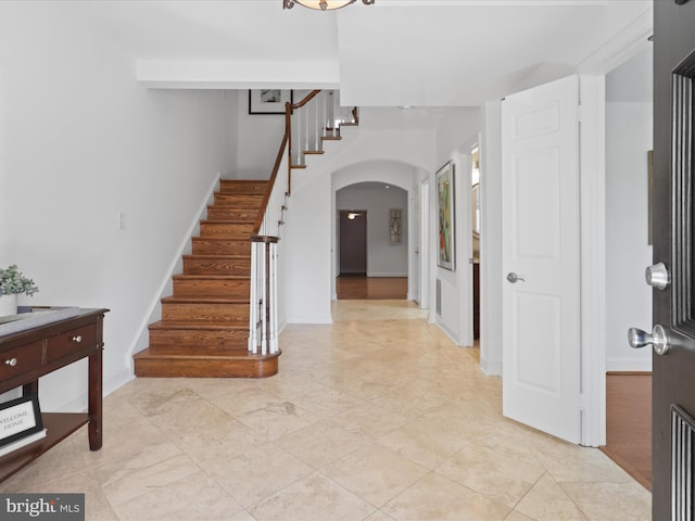 entryway featuring stairway, baseboards, and arched walkways