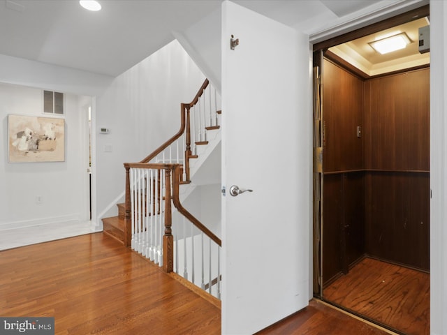 stairs with wood finished floors and visible vents