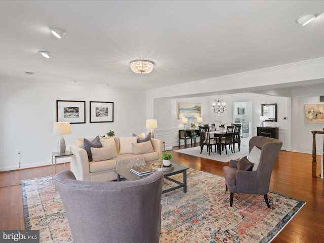 living room with baseboards, an inviting chandelier, and wood finished floors