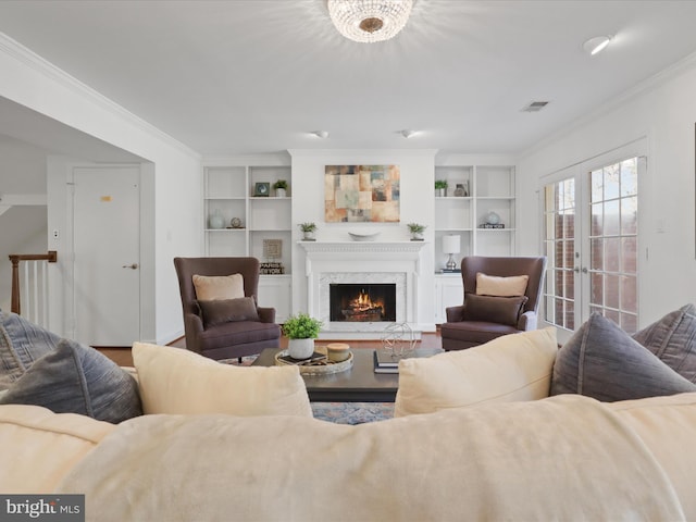 living area with visible vents, built in shelves, ornamental molding, french doors, and a fireplace