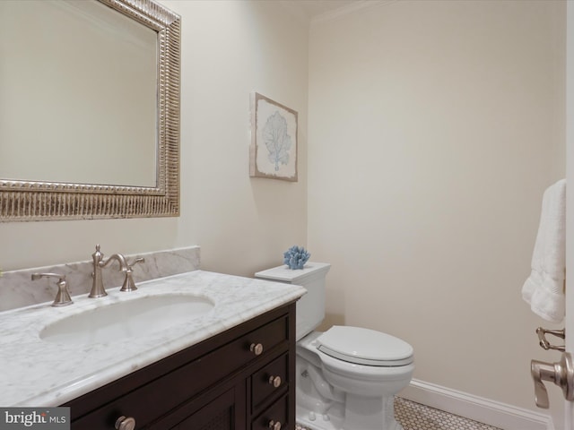 half bathroom featuring toilet, vanity, baseboards, and ornamental molding