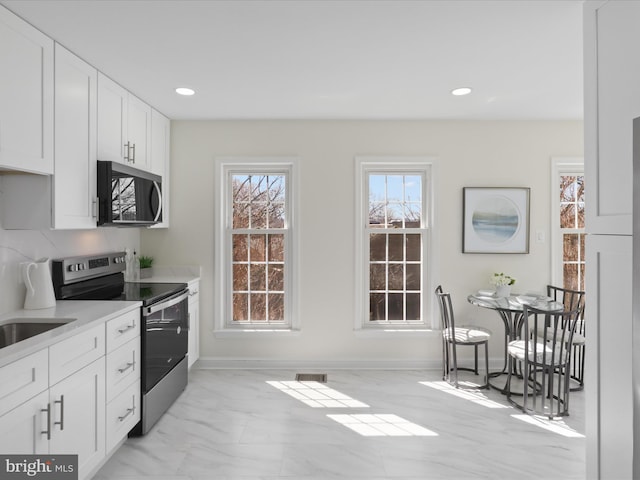 kitchen with recessed lighting, stainless steel appliances, light countertops, white cabinetry, and marble finish floor