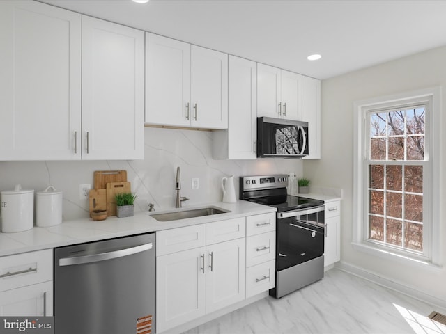 kitchen featuring light stone countertops, recessed lighting, a sink, white cabinets, and appliances with stainless steel finishes